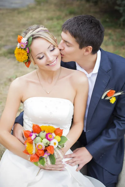 Casal jovem beijando no vestido de casamento. Noiva segurando buquê de flores — Fotografia de Stock