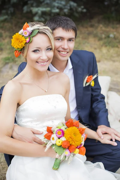 Young couple kissing in wedding gown. Bride holding bouquet of flowers — Stock Photo, Image