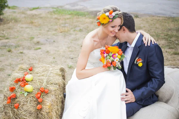 คู่รักหนุ่มสาวจูบกันในชุดแต่งงาน เจ้าสาวถือช่อดอกไม้ — ภาพถ่ายสต็อก