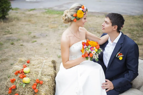 Young couple kissing in wedding gown. Bride holding bouquet of flowers — Stock Photo, Image