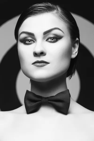 Pretty woman with evening make up and red lips in a bow-tie in a center of a dartboard background. Black and White — Stock Photo, Image