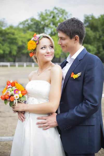 接吻的结婚礼服的年轻夫妇。新娘控股束鲜花 — 图库照片