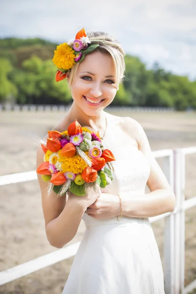 Schöne Braut im weißen Brautkleid mit Blumenstrauß und Lächeln — Stockfoto