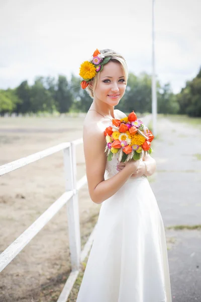 Belle mariée en robe de mariée blanche tenant bouquet de fleurs et souriant — Photo