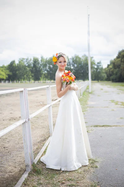 Belle mariée en robe de mariée blanche tenant bouquet de fleurs et souriant — Photo