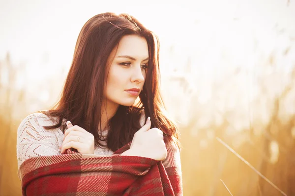 Brunette vrouw buitenshuis in selectievakje patroon plaid glimlachen en kijken naar camera. kopie ruimte — Stockfoto