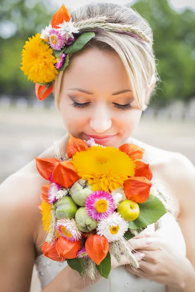 Bella sposa in abito da sposa bianco con bouquet di fiori e sorridente — Foto Stock