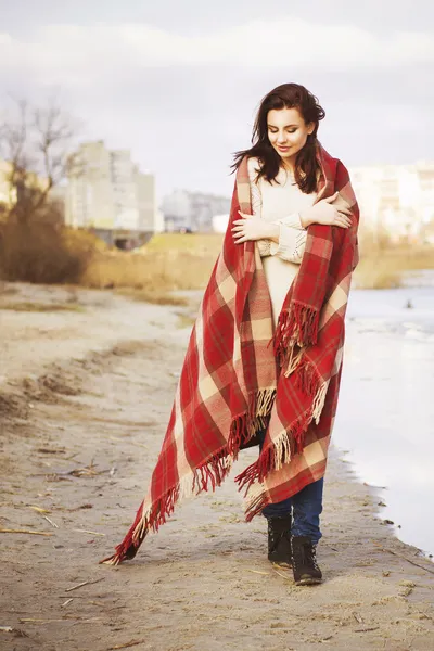 Brunette woman outdoors in check pattern plaid smiling and looking down walking near the lake. Copy space — Stock Photo, Image