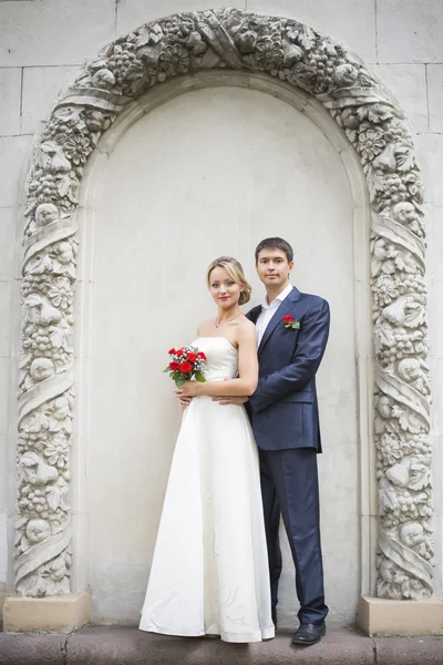 Jeune couple embrassant en robe de mariée. Bouquet de mariée avec roses rouges — Photo