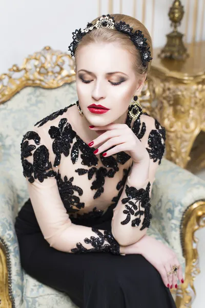 Bella donna reale bionda seduta su una sedia retrò in splendido vestito di lusso, guardando la fotocamera. Interni — Foto Stock