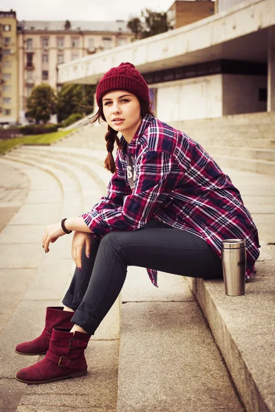Brunett kvinna i hipster outfit sitter på trappan på gatan. tonas bild — Stockfoto