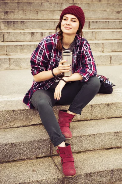 Brunette vrouw in hipster outfit zittend op stappen op de straat. getinte afbeelding — Stockfoto