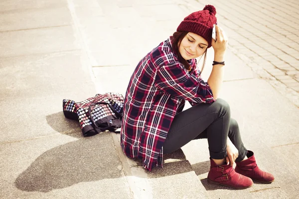 Brunette vrouw in hipster outfit zittend op stappen op de straat. getinte afbeelding. kopie ruimte — Stockfoto