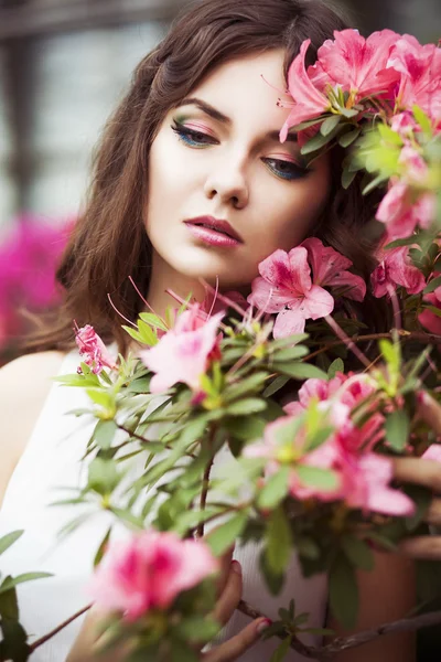 Retrato de uma bela mulher morena em vestido rosa e colorido compõem ao ar livre no jardim azálea — Fotografia de Stock