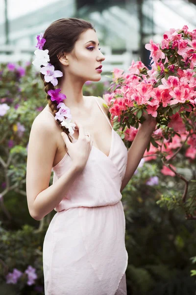 Porträt einer schönen brünetten Frau in rosa Kleid und buntem Make-up im Freien im Azaleen-Garten — Stockfoto