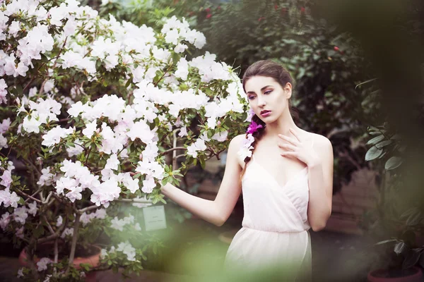 Portrait of a beautiful brunette woman in pink dress and colorful make up outdoors in azalea garden. Copy Space — Stock Photo, Image