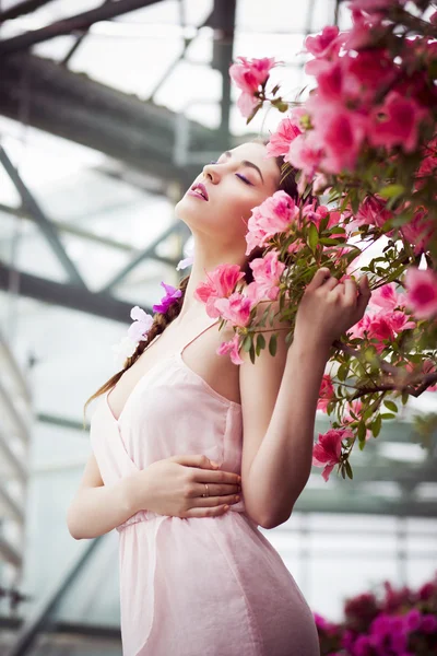 Retrato de una hermosa mujer morena en vestido rosa y maquillaje colorido al aire libre en el jardín de azalea —  Fotos de Stock