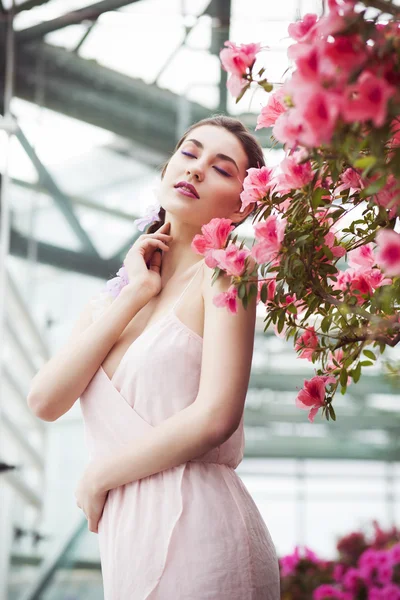 Porträtt av en vacker brunett kvinna i rosa klänning och färgglada göra utomhus i azalea garden — Stockfoto