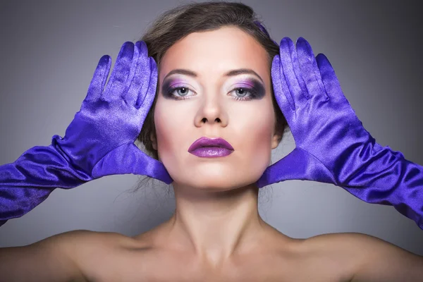 Beautiful brunette woman wearing gloves with purple make up — Stock Photo, Image