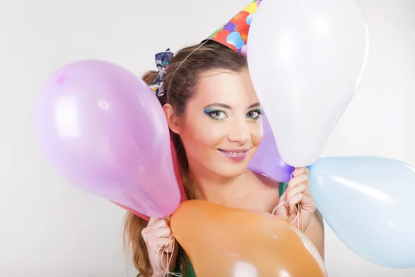 Mulher morena em um tampão de aniversário segurando balões e sorrir feliz — Fotografia de Stock