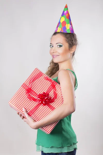 Bruna donna in un cappello di compleanno che tiene regali e sorriso — Foto Stock