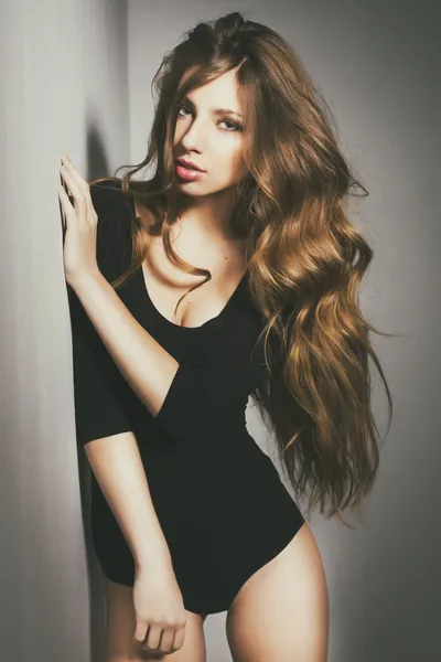 Mulher sexy bonita com cabelo encaracolado longo usando corpo posando em casa em tonificação retro — Fotografia de Stock