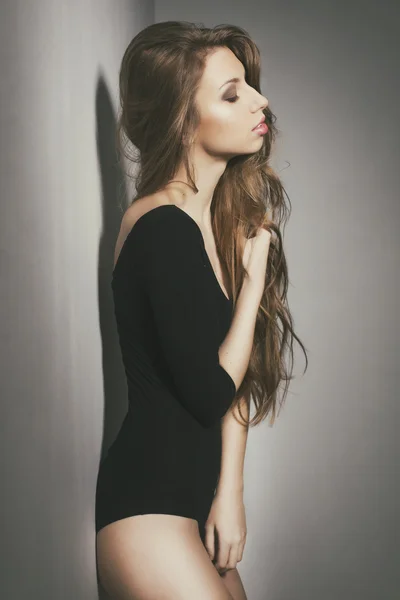 Schöne sexy Frau mit langen lockigen Haaren trägt Körper posiert zu Hause in Retro-Toning — Stockfoto