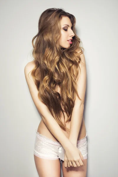 섹시 한 포즈 웃 고 있는 벽 근처만 팬티를 입고 긴 머리를 가진 아름 다운 금발의 여 인 — 스톡 사진