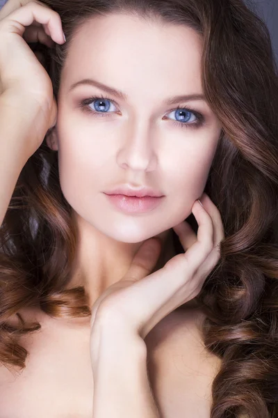 Beautiful brunette woman with blue eyes without make up, natural flawless skin and hands near her face — Stock Photo, Image