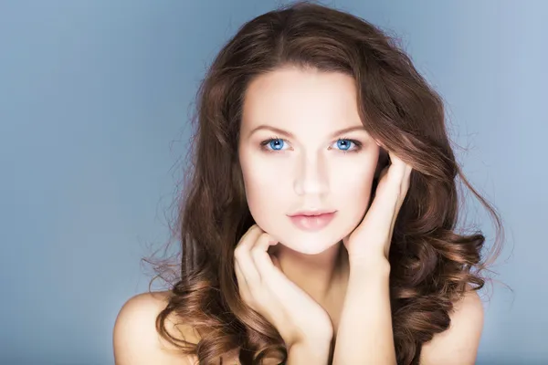 Beautiful brunette woman with blue eyes without make up, natural flawless skin and hands near her face — Stock Photo, Image