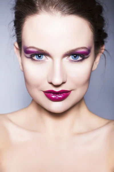 Schöne brünette Frau mit kreativem Make-up violette Lidschatten volle rote Lippen, blaue Augen und lockiges Haar — Stockfoto