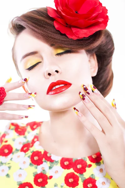Mujer morena en vestido amarillo y rojo con flor de amapola en el pelo, anillo de amapola y uñas creativas, ojos cerrados sobre fondo blanco —  Fotos de Stock