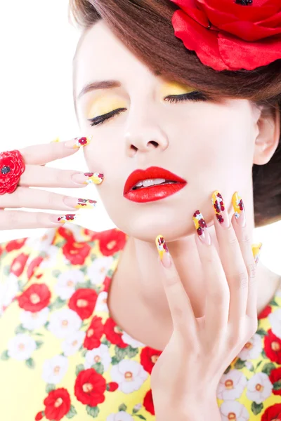 Mujer morena en vestido amarillo y rojo con flor de amapola en el pelo, anillo de amapola y uñas creativas, ojos cerrados sobre fondo blanco — Foto de Stock