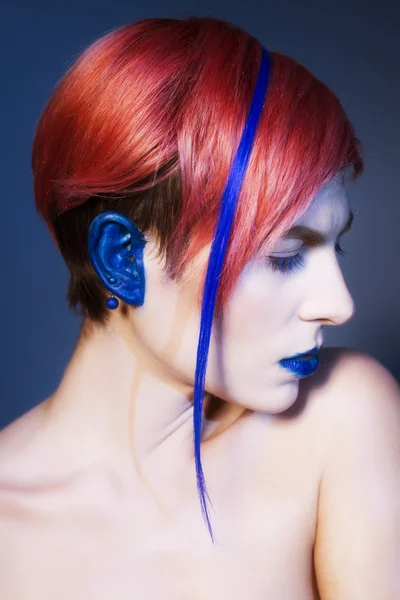 Jonge persoon met blauwe ogen schaduwen, blauwe oren en roze haren met blauwe strand op het kijken naar camera en handen in de buurt van gezicht. Zwarte achtergrond — Stockfoto