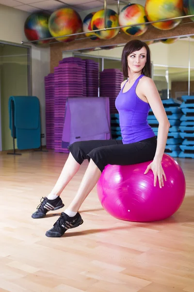 Fit Femme faire des exercices avec une balle sur un tapis dans un gymnase souriant — Photo