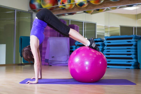 Fit Femme faire des exercices avec une balle sur un tapis dans un gymnase souriant — Photo