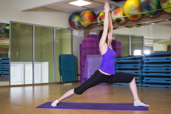 Fit Woman haciendo ejercicio de yoga en una alfombra en un gimnasio sonriendo — Foto de Stock