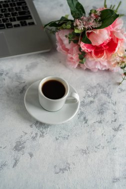 Masaüstünde bir dizüstü bilgisayar var, bir fincan kahvenin yanında.