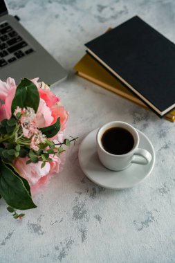 Masaüstünde bir dizüstü bilgisayar var, bir fincan kahvenin yanında.