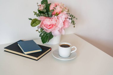 Bir kupa kahve beyaz arka planda bir masanın üzerinde duruyor.