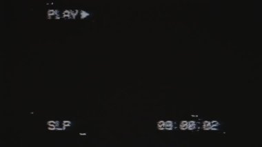 VHS effect, noise and artifacts, glitches from an old tape. Old black screen with PLAY text and timecode. Old bad VHS tape playing. Retro.