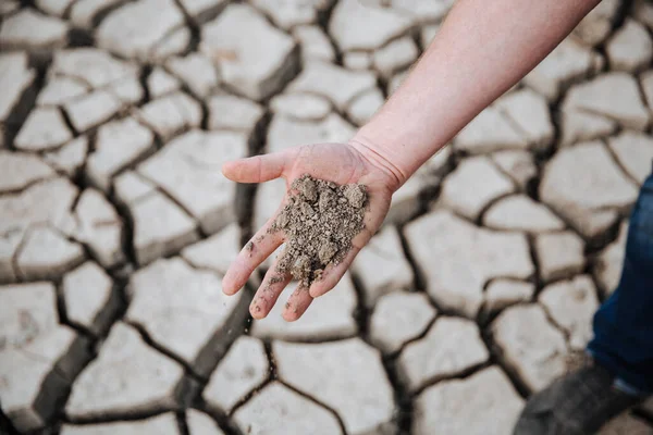 Az az ember a tenyerében tartja a nagyon száraz földet. A globális felmelegedés miatti csapadékhiány miatti talajerózió fogalma — Stock Fotó