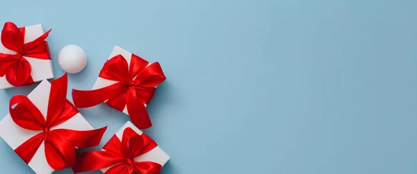 Scatole regalo su sfondo blu concetto di biglietto di auguri vacanze, scatola bianca regalo legato con nastro rosso, banner vacanza — Foto Stock