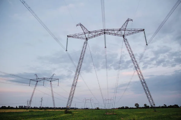 Yüksek voltajlı elektrik hatları ve alacakaranlıkta yüksek voltajlı elektrik iletim kulesi.