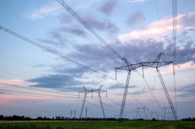 Yüksek voltajlı elektrik hatları ve alacakaranlıkta yüksek voltajlı elektrik iletim kulesi.