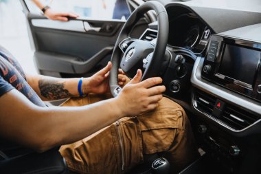 Bir adamın eli arabanın direksiyonunu tutar.. 