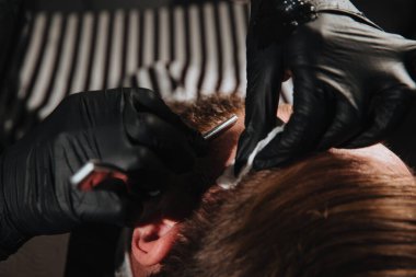 Adam berber dükkanında moda saç kesimi yaptırıyor.