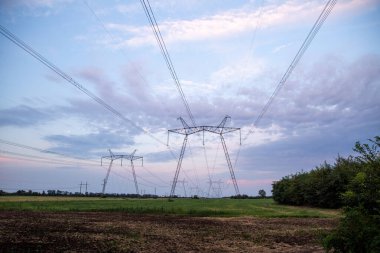 Yüksek voltajlı elektrik hatları ve alacakaranlıkta yüksek voltajlı elektrik iletim kulesi.