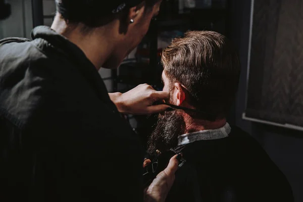 Femme coiffeur professionnel servant client avec grosse barbe épaisse par tondeuse — Photo