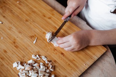 Tahtada taze şampiyon mantarları. Kız mantarları bıçakla kesiyor..